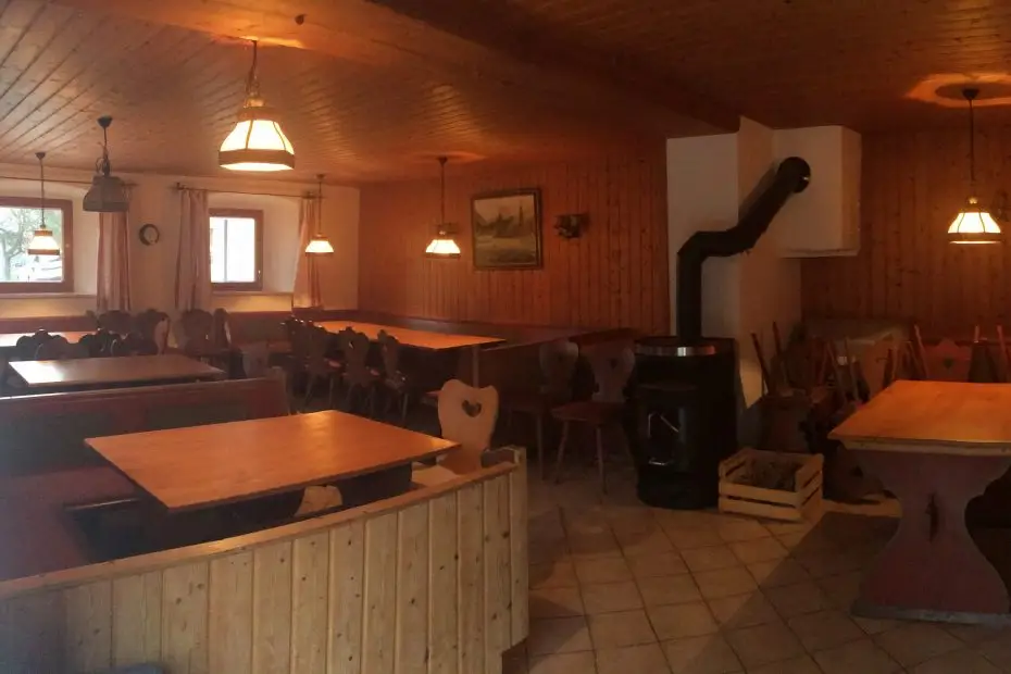 Aufenthaltsraum mit Holzofen und Tischen mit Eckbänken am Campingplatz Stein