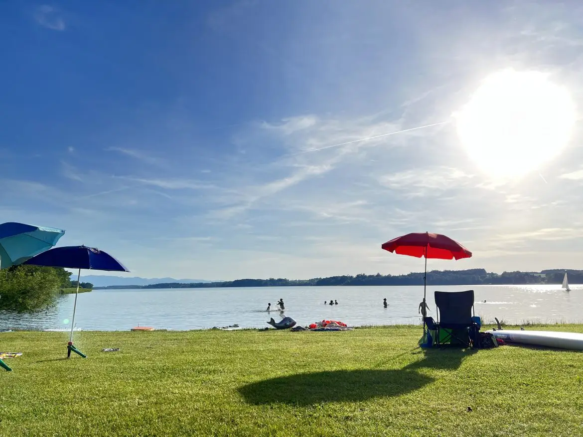 Liegewiese am See mit Sonnenschirm am Camping Stein