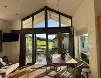 Chalet Leni - Wohnraum mit Sofa, Fernseher, Essbereich und Küche mit Kühlschrank, Spülmaschine und Mikrowelle