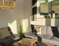 Chalet Leni - Wohnraum mit Sofa, Fernseher, Essbereich und Küche mit Kühlschrank, Spülmaschine und Mikrowelle